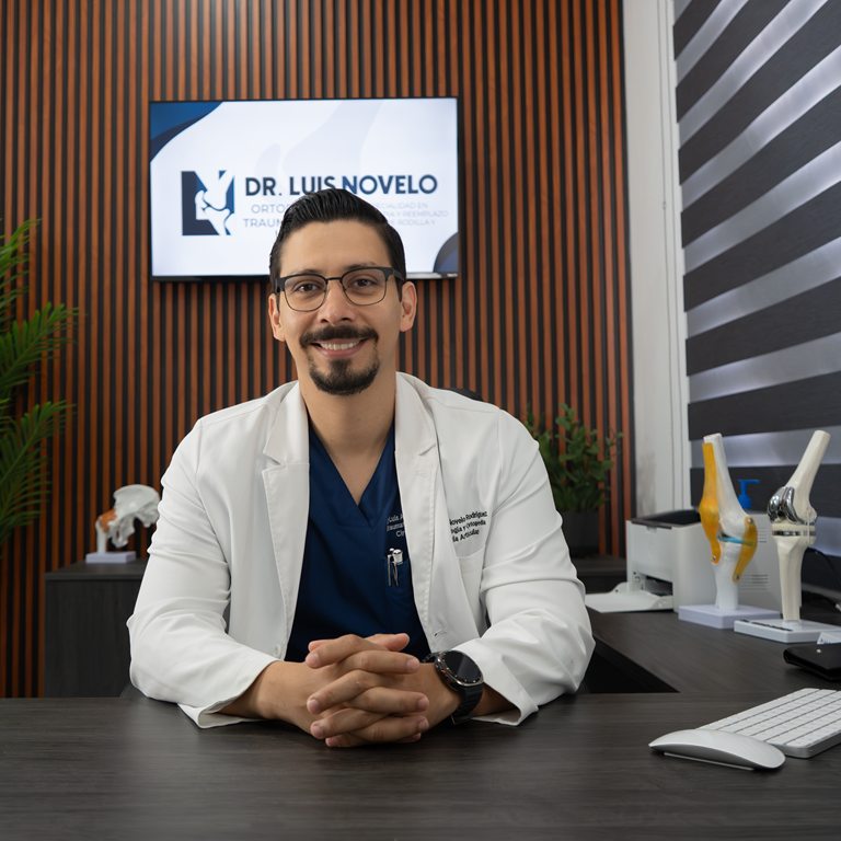 Dr. Luis Novelo, ortopedista y traumatólogo, en su consultorio de Mérida junto a modelos de prótesis de rodilla